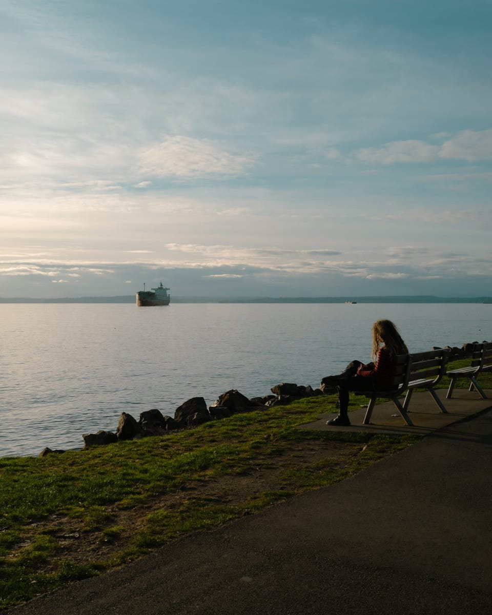 A person sitting on a bench at the Seattle Water Front admiring the Puget Sound